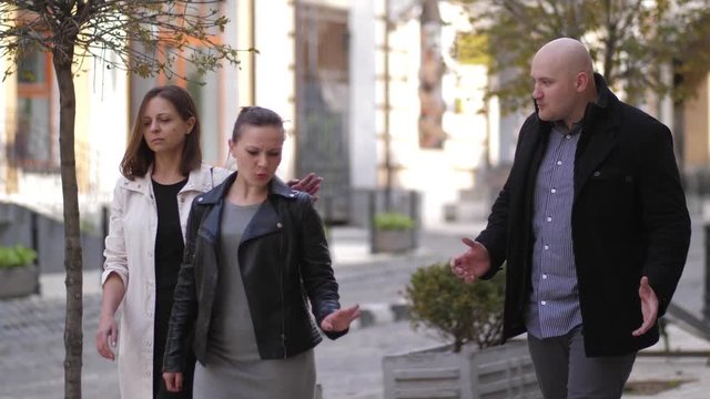 Close-up of brave females applying skill of Krav Maga martial arts for self defense beating huge man after knee kick in groin. Fearless women neutralizing angry male attacker during walk