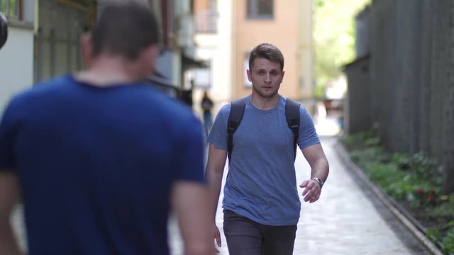 Close-up of thugs attacking young man walking down deserted lane. Group of three muggers fighting with lonely man using skill of Krav Maga martial arts and knocking attackers to gain time and run away