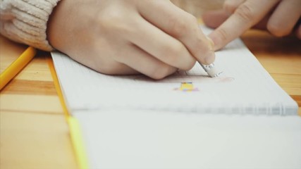 Hand of child drawing and erasing a picture in her sketch pad. - Powered by Adobe