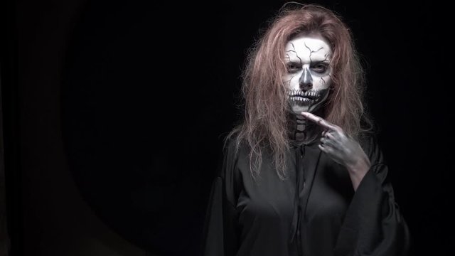 concept, beautiful makeup for halloween. Portrait of a young sexy girl with skull makeup. on a black background, face in the dark. close-up