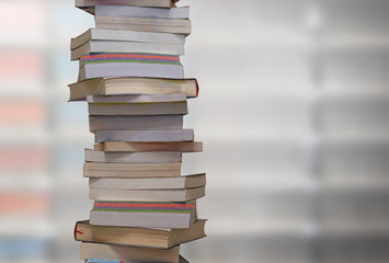 Stacking books with blur bookshelfs background in the library. Education and knowledge high as a mountain concept.