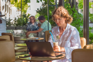 Beautiful girl with a laptop working in cafe. Business woman working outdoor. Freelancing background. Working woman freelancer close up