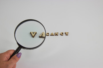 the word vacancy of wooden letters and a magnifying glass