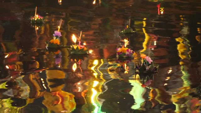 Paper lotus flower with candle floating on a river at night in Loy krathong festival, traditional Siamese new year festival celebrated in Thailand.