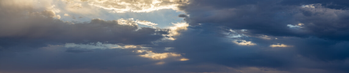 Panorama of colorful clouds at sunset over an urban environment with mountains in the distance