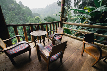 Fototapeta na wymiar Table and chairs at the terrace with mountain and forest background,porch of a house in the jungle.