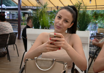 A girl sitting in cafe and holding mobile phone