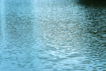 Evening photo water texture, blue dark shadows. The water surface of the lake pond sea. Small ruffle wave from the wind