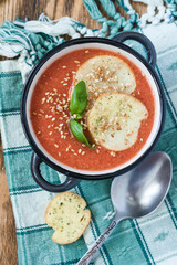 Traditional gazpacho Soup on a green napkin decorated with Basil and crackers top view