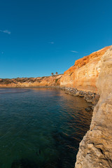 Fototapeta na wymiar Beach coastline with rock cliff and deep blue sky.
