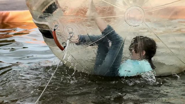 teen girl trying to resist zorbing in an amusement park