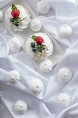 Dessert Pavlova with raspberries, blueberries and mint on a white fabric.