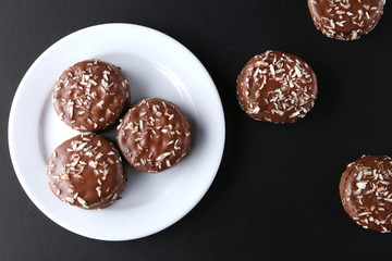 Chocolate cookies with coconut shaving chocolate coating and coconut on wooden black  background.