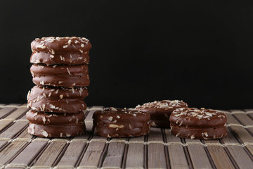 Chocolate cookies with coconut shaving chocolate coating and coconut on wooden black  background.