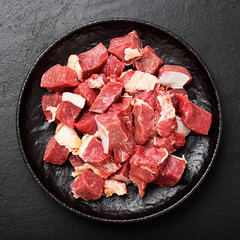 Raw chopped beef meat with spices on black background.