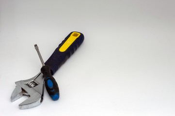 Adjustable wrench and flat head screwdriver lie on white background.