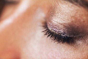 Festive glowing eyeshadow make up in brown and pink colors with shiny and glitter sparkles close up. Beauty trendy concept.