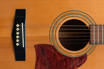 close macro view of the six frets  and sound hole on an acoustic wooden  guitar body