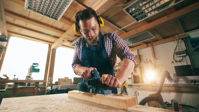 Joinery with a craftsman sawing wood. Craftsman working in carpentry.