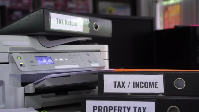 Document Reports busy office concept. Tax return, property tax folders stack on printer with label on binder paperwork documents report in offices.HR-human resources business bookkeeping accountancy
