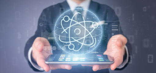 Businessman holding an atom icon surrounded by data
