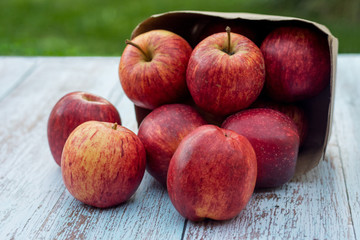 Organic ripe apples in a recyclable paper box on a wooden table in the garden. Cooking ingredients. Harvest. Sustainable living. Say “no” to plastic packaging.