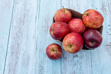 Organic ripe apples in a recyclable paper box on a wooden table. Cooking ingredients. Harvest. Sustainable living. Say “no” to plastic packaging.