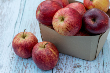 Organic ripe apples in a recyclable paper box on a wooden table. Cooking ingredients. Harvest. Sustainable living. Say “no” to plastic packaging.