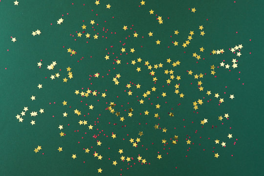 Golden And Red Stars Shaped Confetti Frame On Green Background. Top View, Flat Lay