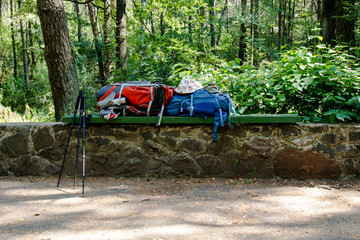 Obraz na płótnie Canvas Two hiking backpacks and trekking poles on the bench during the halt
