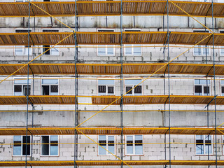 Wall repair and renovation for saving and energy efficiency of the building. Building under construction in scaffolding across the wall.