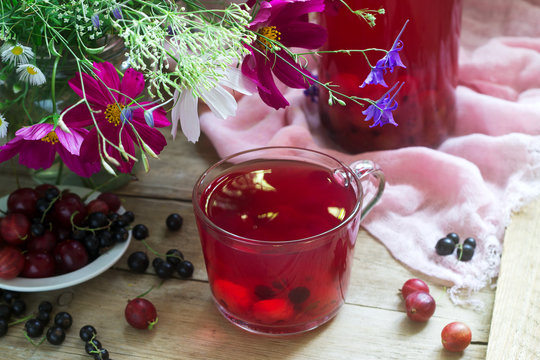 Berry compote in a glass cup, berries and a bouquet of wild flowers on a deoanean background. Rustic style.