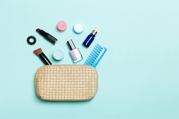 Top view of set of make up and skin care products spilling out of cosmetics bag on blue background. Beauty concept
