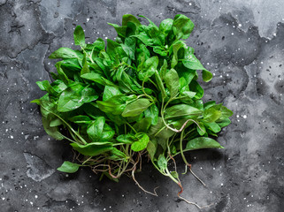 Fresh organic spinach on a dark background, top view. Copy space