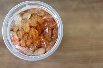 Close up of ice cubes with cola in the plastic glass,top view