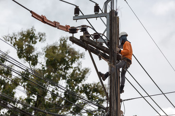electricians repairing wire of the power line on electric power pole