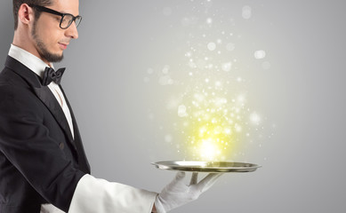 Elegant young waiter serving mysterious light on tray