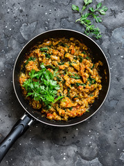 Eggplant spinach vegetarian curry in a pan on a dark background, top view. Indian cuisine