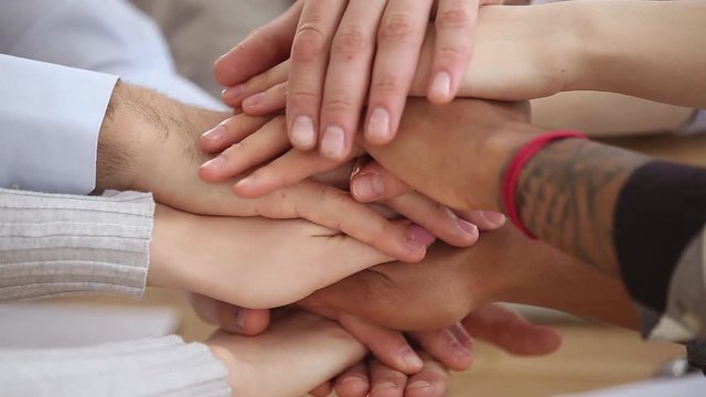 Different ethnicity people hands stacked together close up view
