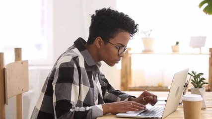 Disgruntled african ethnicity student girl typing looking at computer screen - Powered by Adobe