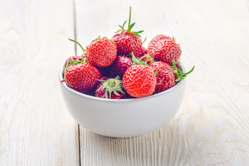 Fresh strawberries in a bowl on a wooden table. close-up