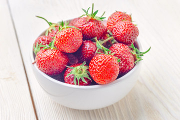 Fresh strawberries in a bowl on a wooden table. close-up