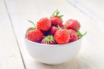 Fresh strawberries in a bowl on a wooden table. close-up
