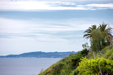Fototapeta na wymiar hill with palm trees above blue sea, Halkidiki Greece