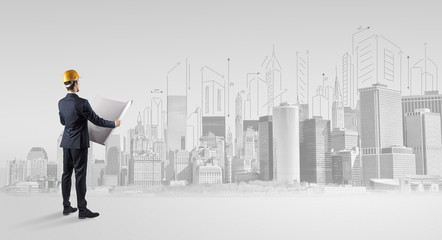 Young supervisor architect standing and replanning a big city panorama