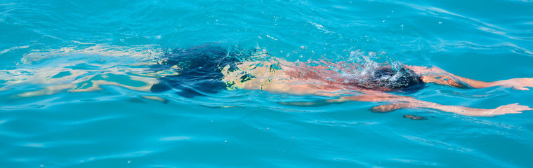 Fototapeta na wymiar A man swims in the water in the water
