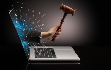 Hand with hammer coming out of a laptop with sparkling effects