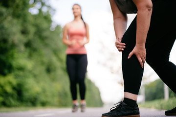 Woman touching her knee, sports injury at outdoor jogging. Health care, sports and medical concept