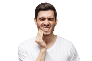 Close-up of young man touching his face and closing eyes with expression of horrible suffer from...