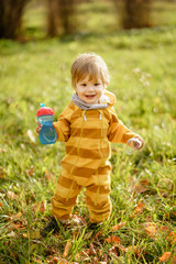 Concept: family, kids. Happy little child, baby boy with water bottle laughing and playing in the autumn on the nature walk outdoors at park